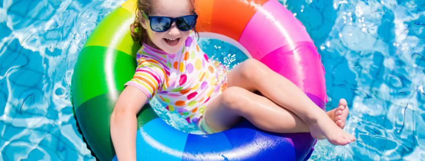 Child with colorful inflatable ring in swimming pool